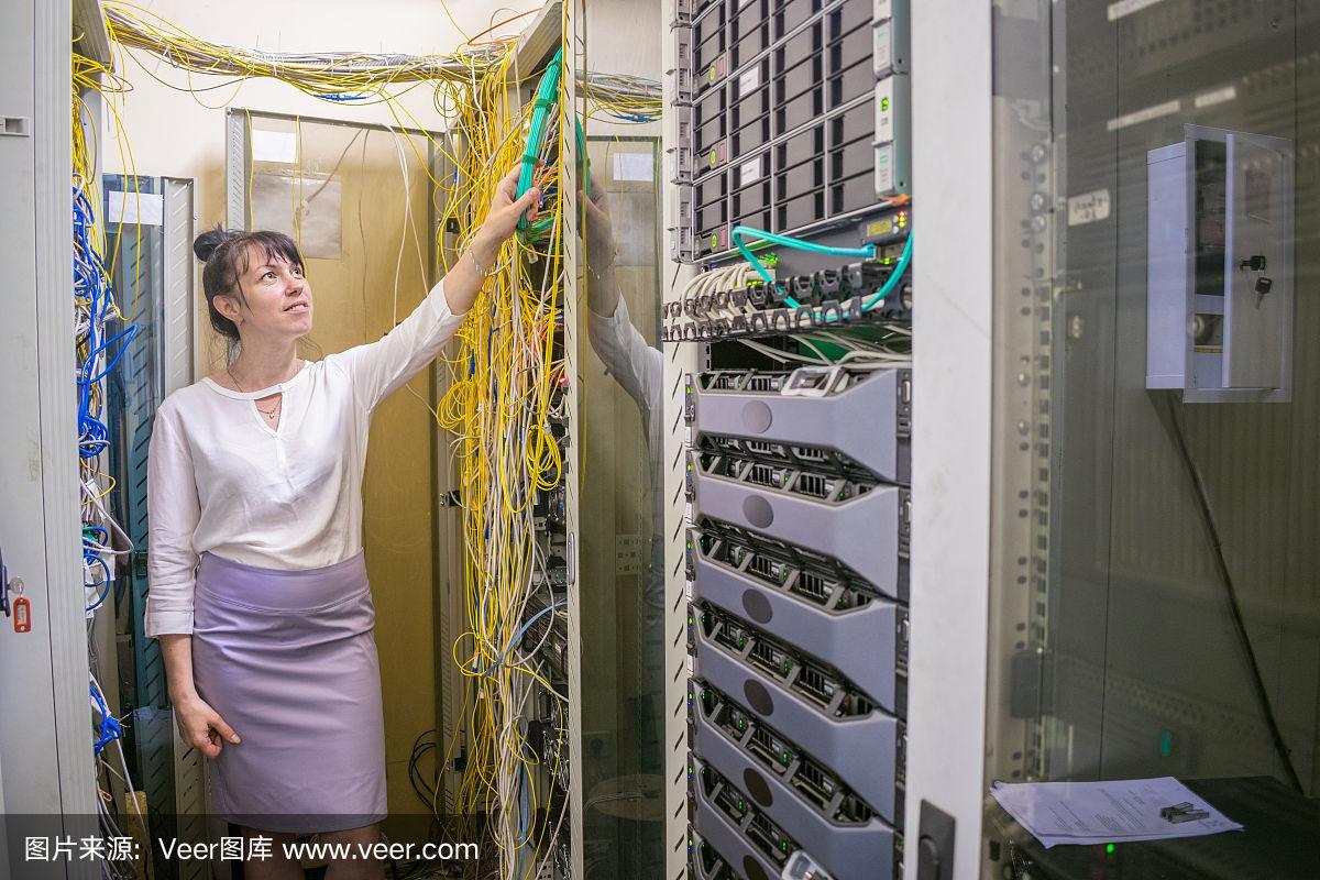女子在数据中心的服务器室检查互联网光纤的连接
